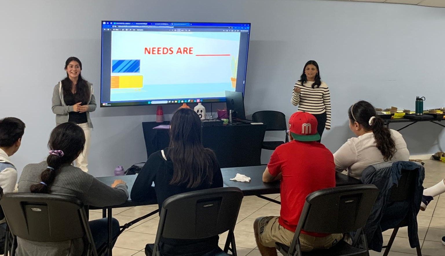 A woman is giving a presentation to a group of people sitting at tables.