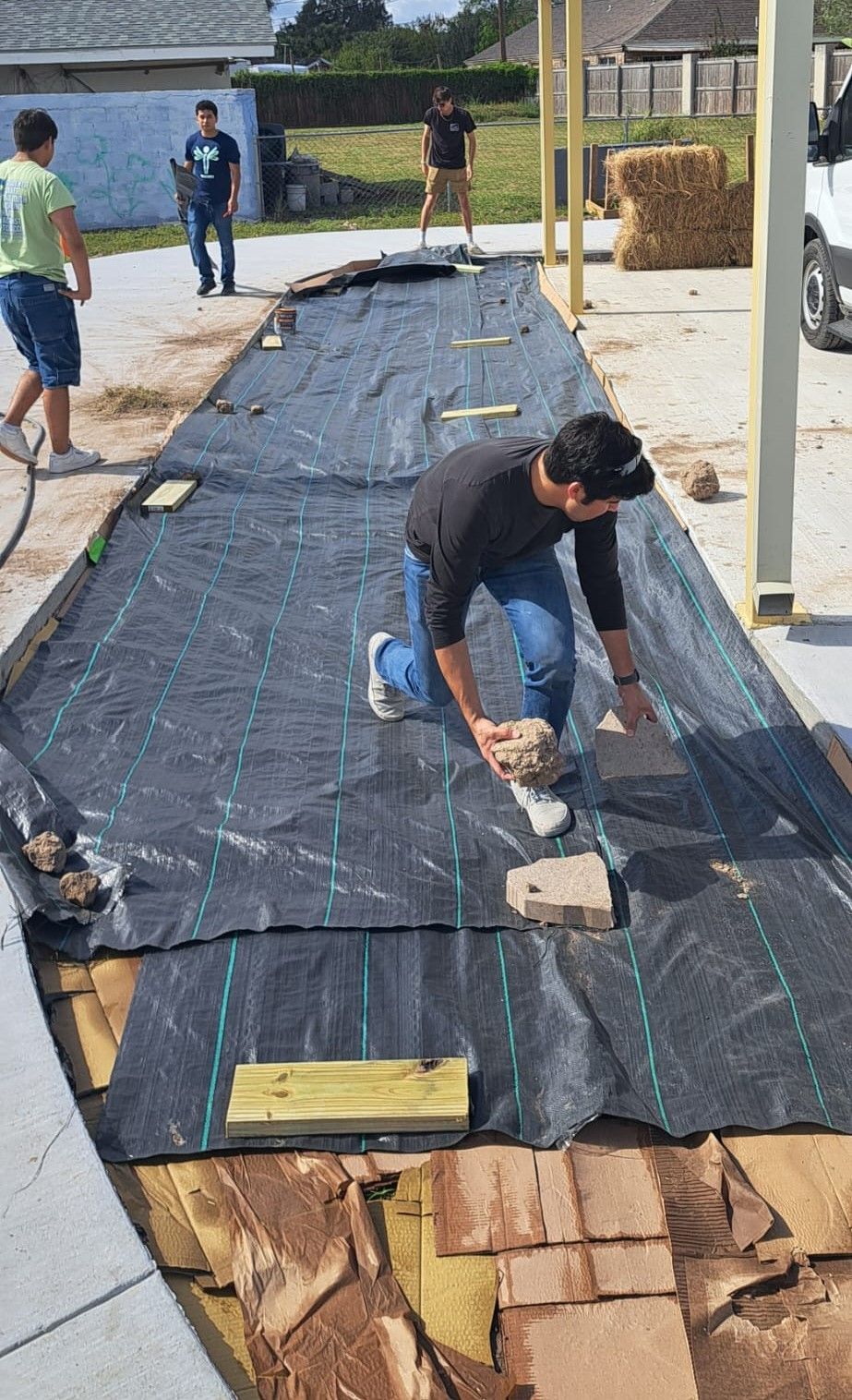A man is kneeling down on a black tarp.