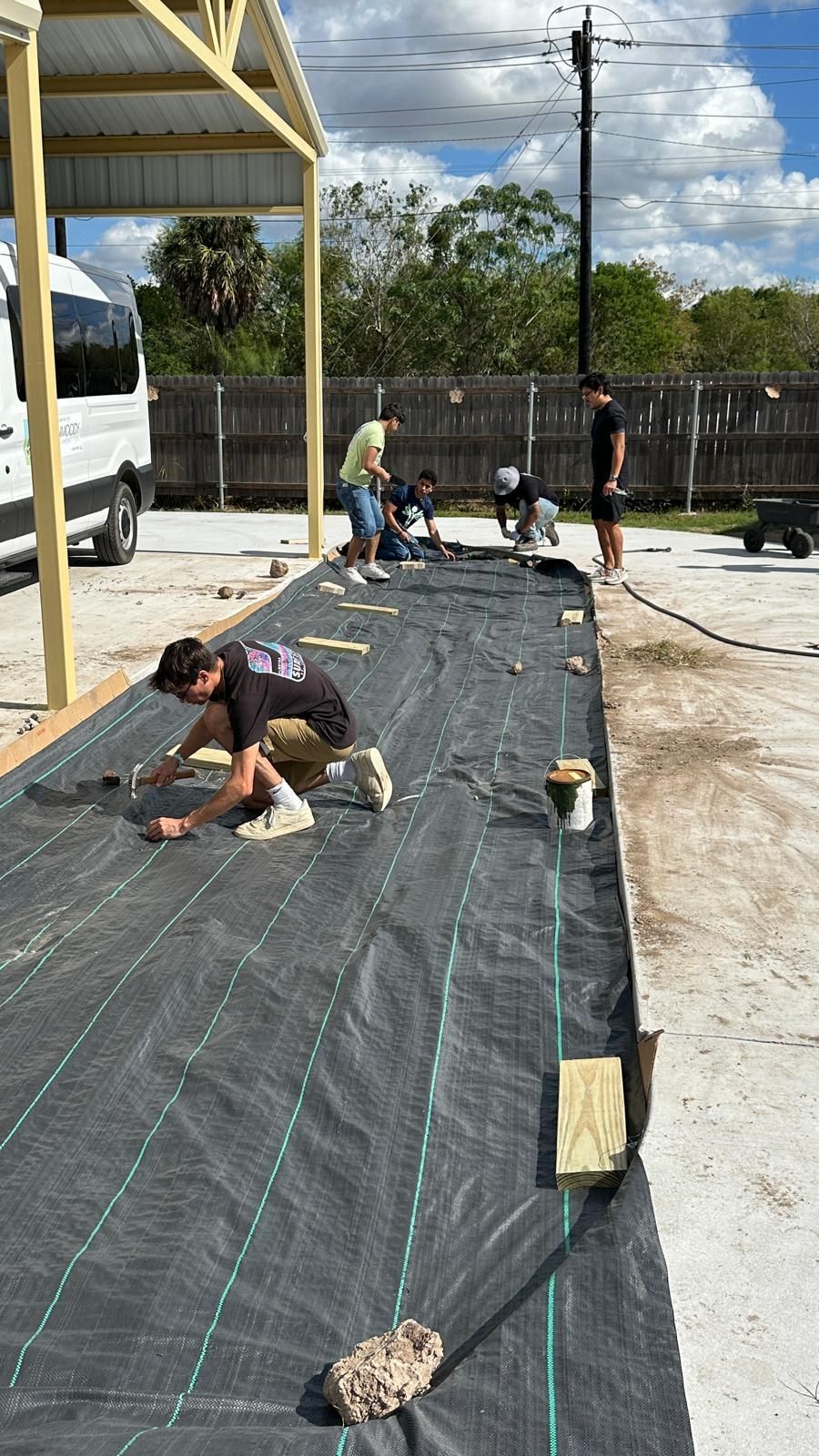 A group of people are working on a concrete driveway.