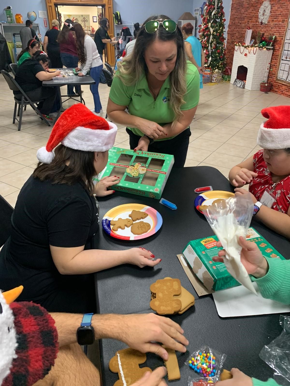 A group of people are sitting around a table decorating gingerbread cookies.