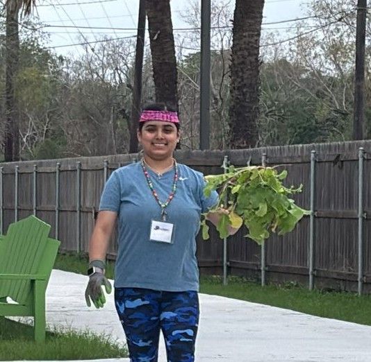 A woman is walking down a sidewalk holding a bunch of leaves.