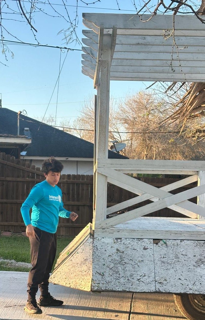 Boy in blue shirt jumps near white pergola.
