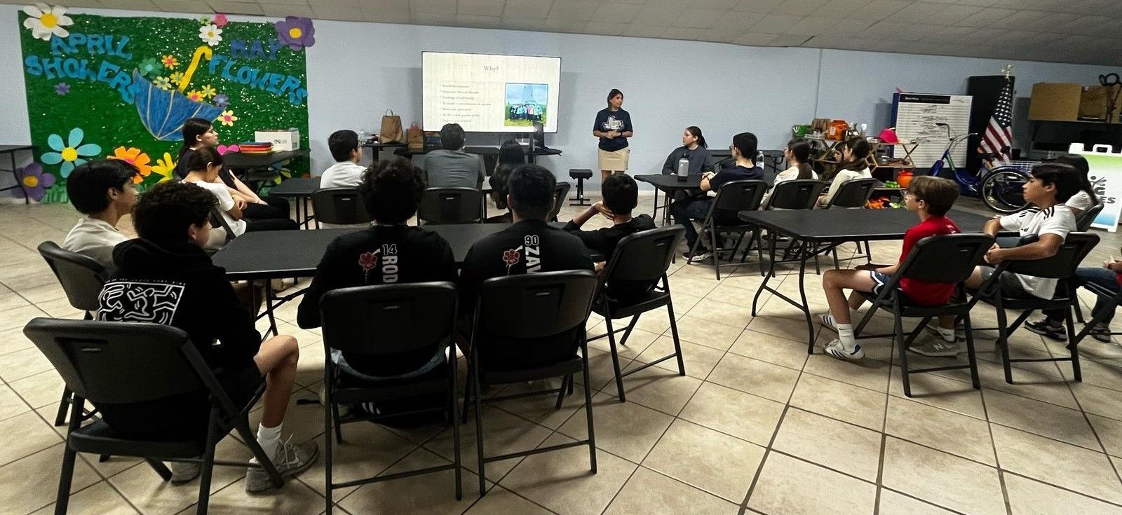 A group of students in a classroom listening to a presentation.