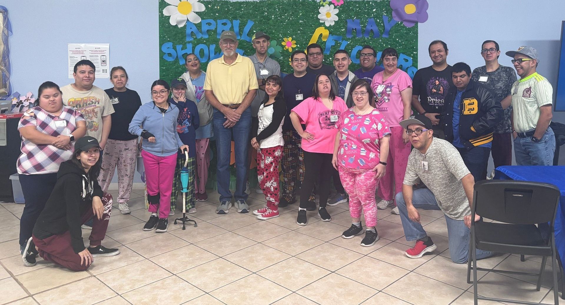 A group of people are posing for a picture in front of a wall with flowers on it.