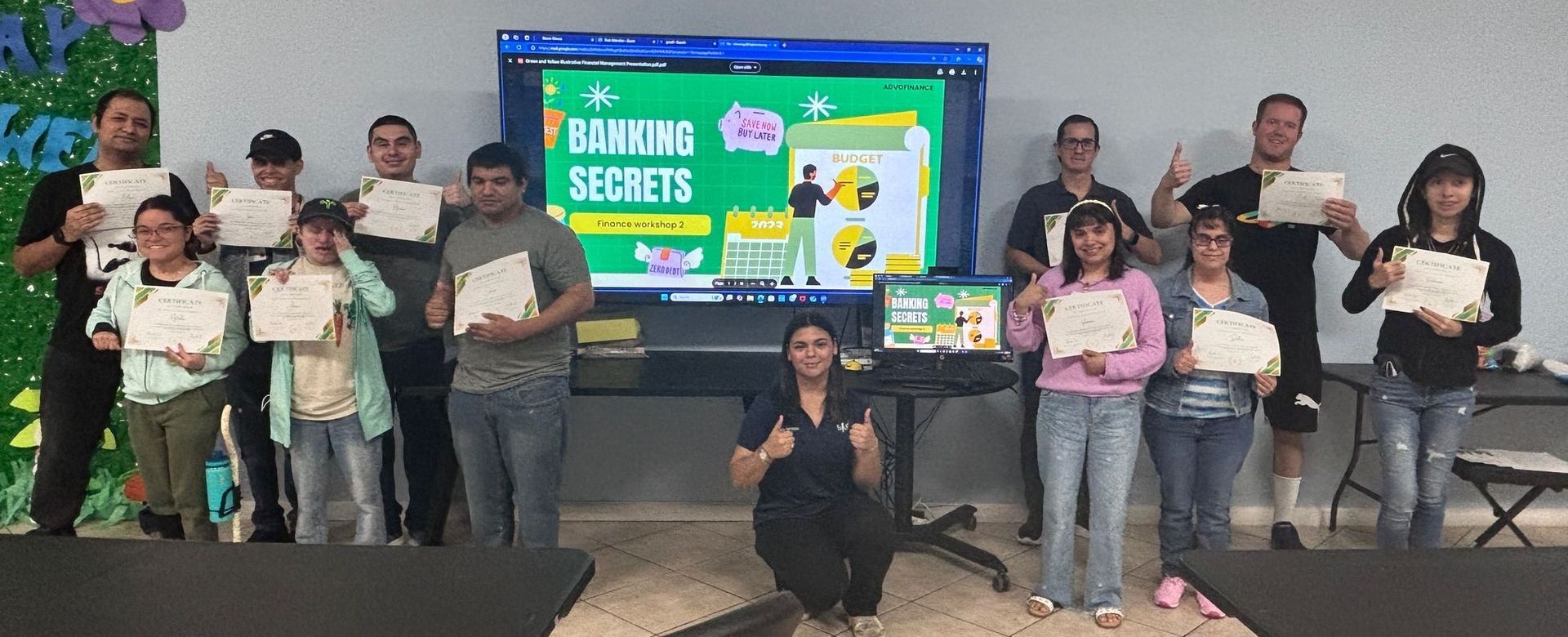 Group of people posing with certificates in front of a screen displaying the words 