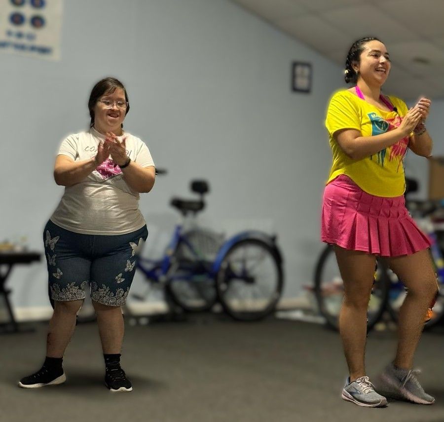 Two women are clapping in a room with bikes in the background