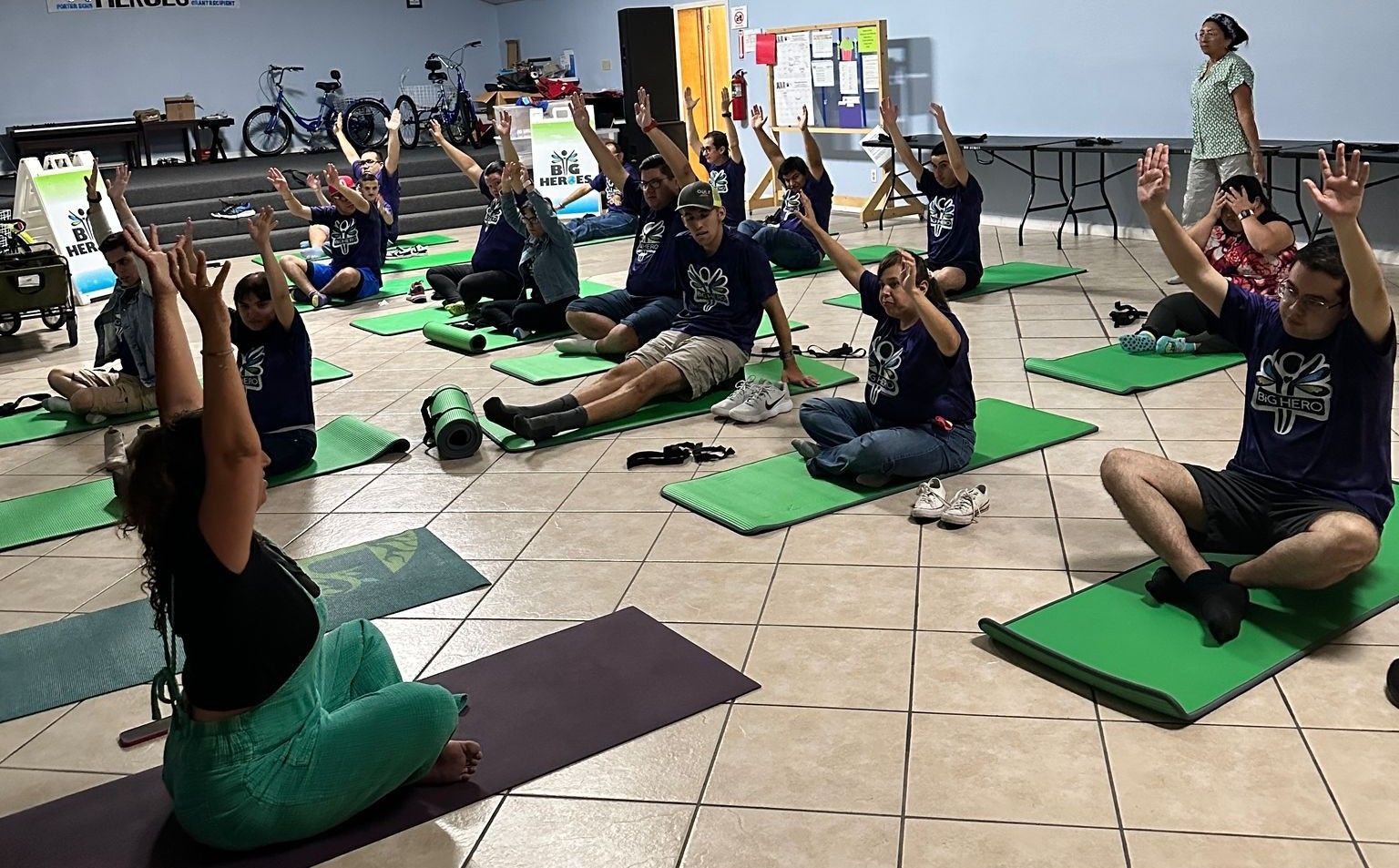 A group of people are sitting on yoga mats in a room.
