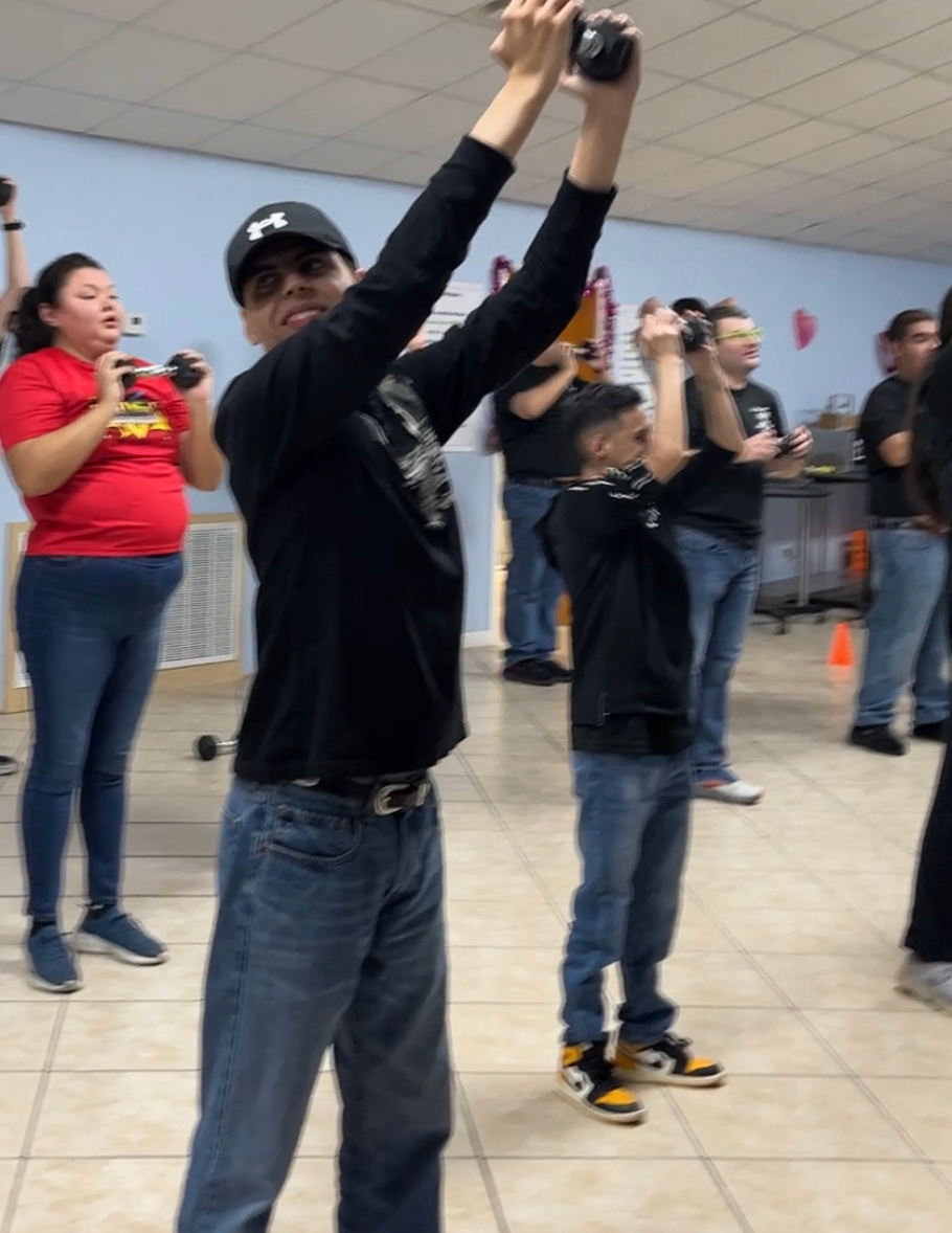 A group of people are standing in a room with their arms in the air