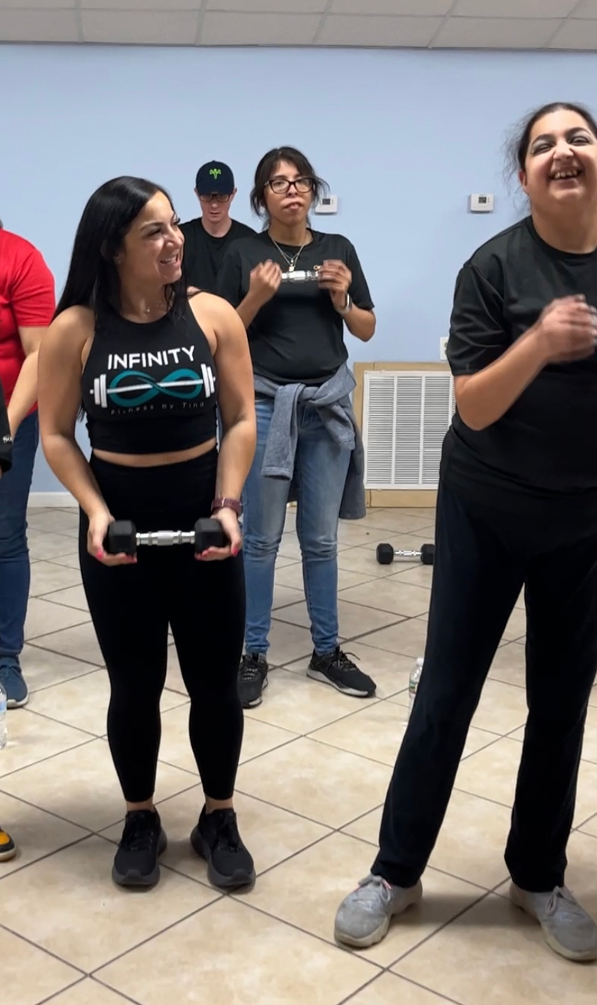 A group of women are standing in a room holding dumbbells.