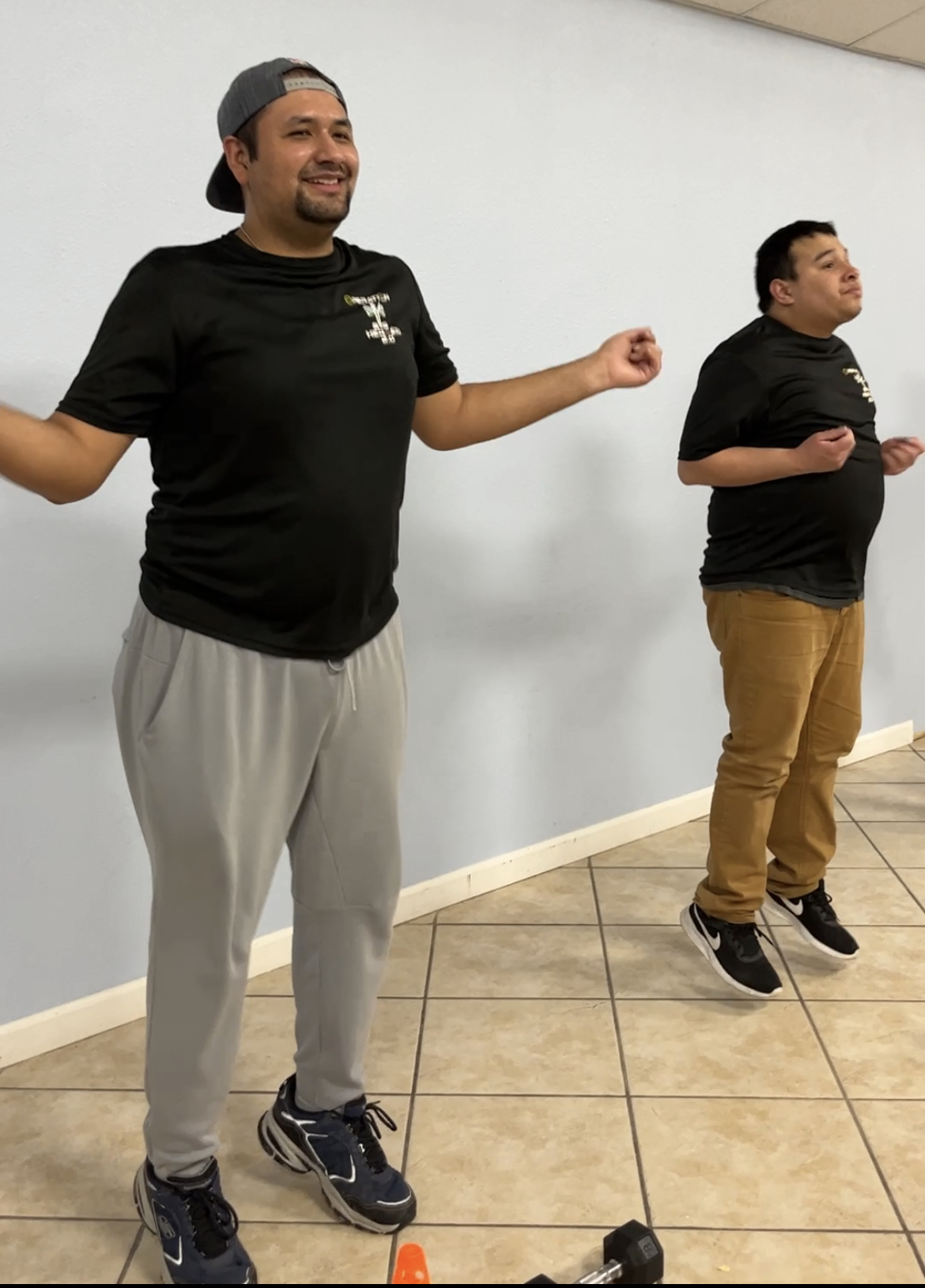 Two men are standing in a room with their arms outstretched