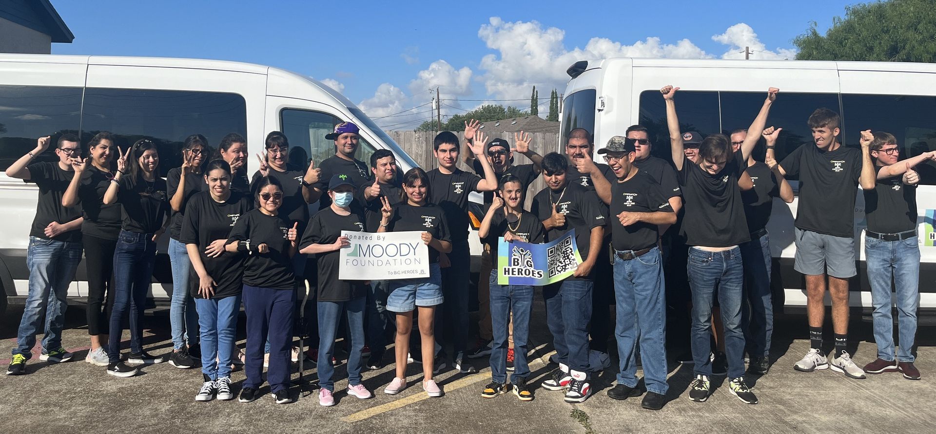 A group of people are posing for a picture in front of two vans.