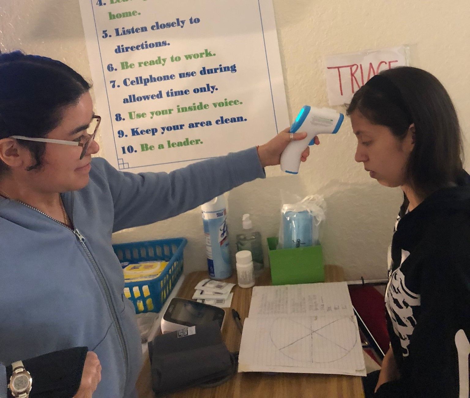 A woman is using a thermometer to check another woman 's temperature