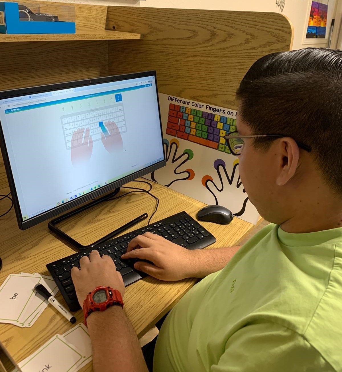 A man in a green shirt is typing on a computer