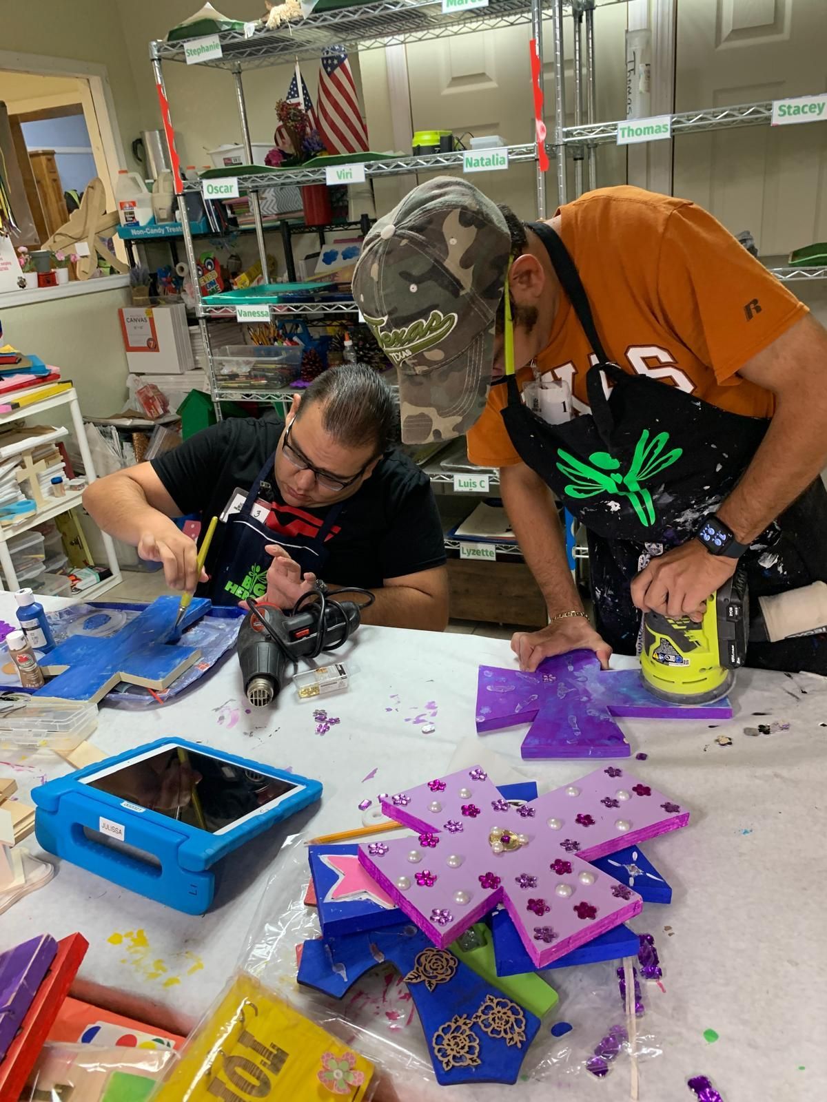 Two men are sitting at a table working on a project.
