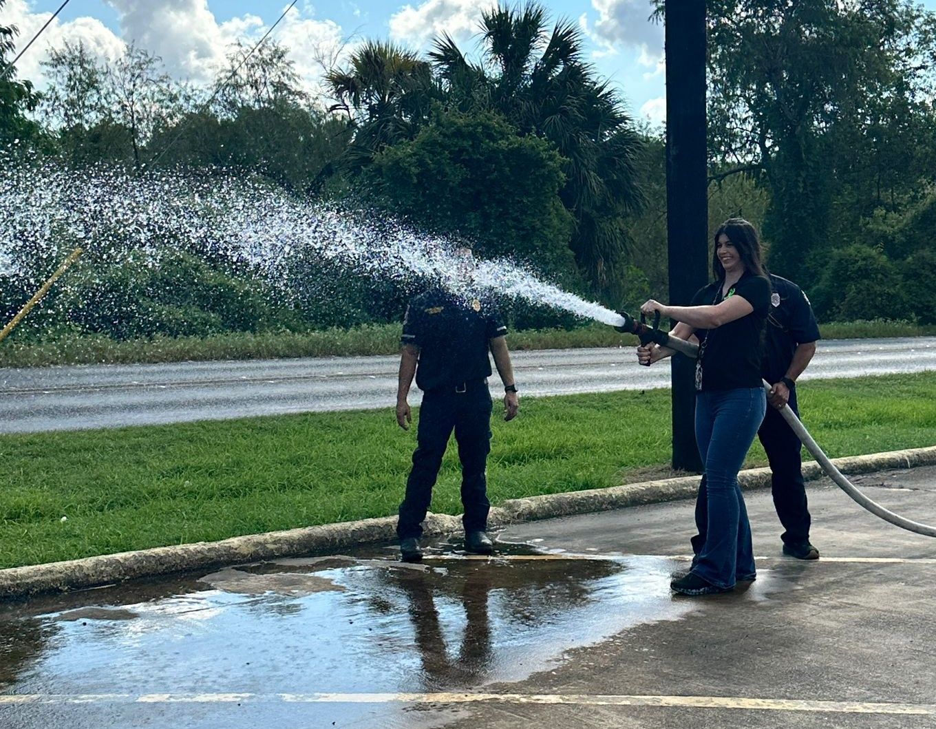 A man and a woman are spraying water from a fire hose.