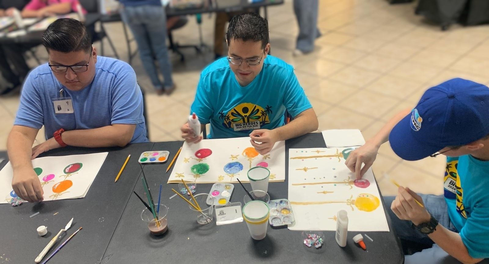 A group of young men are sitting at a table painting.