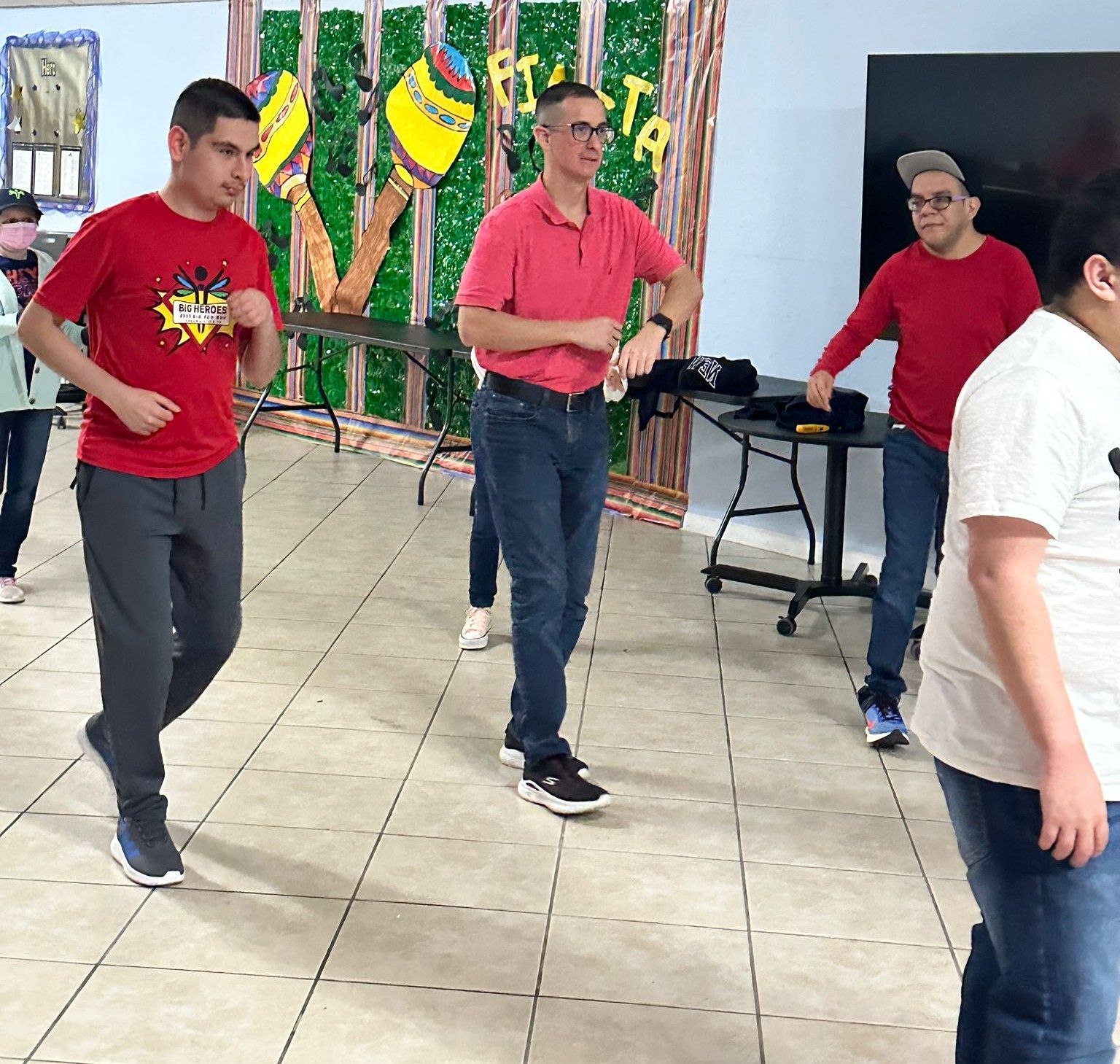A group of people are standing in a room with a sign that says fiesta