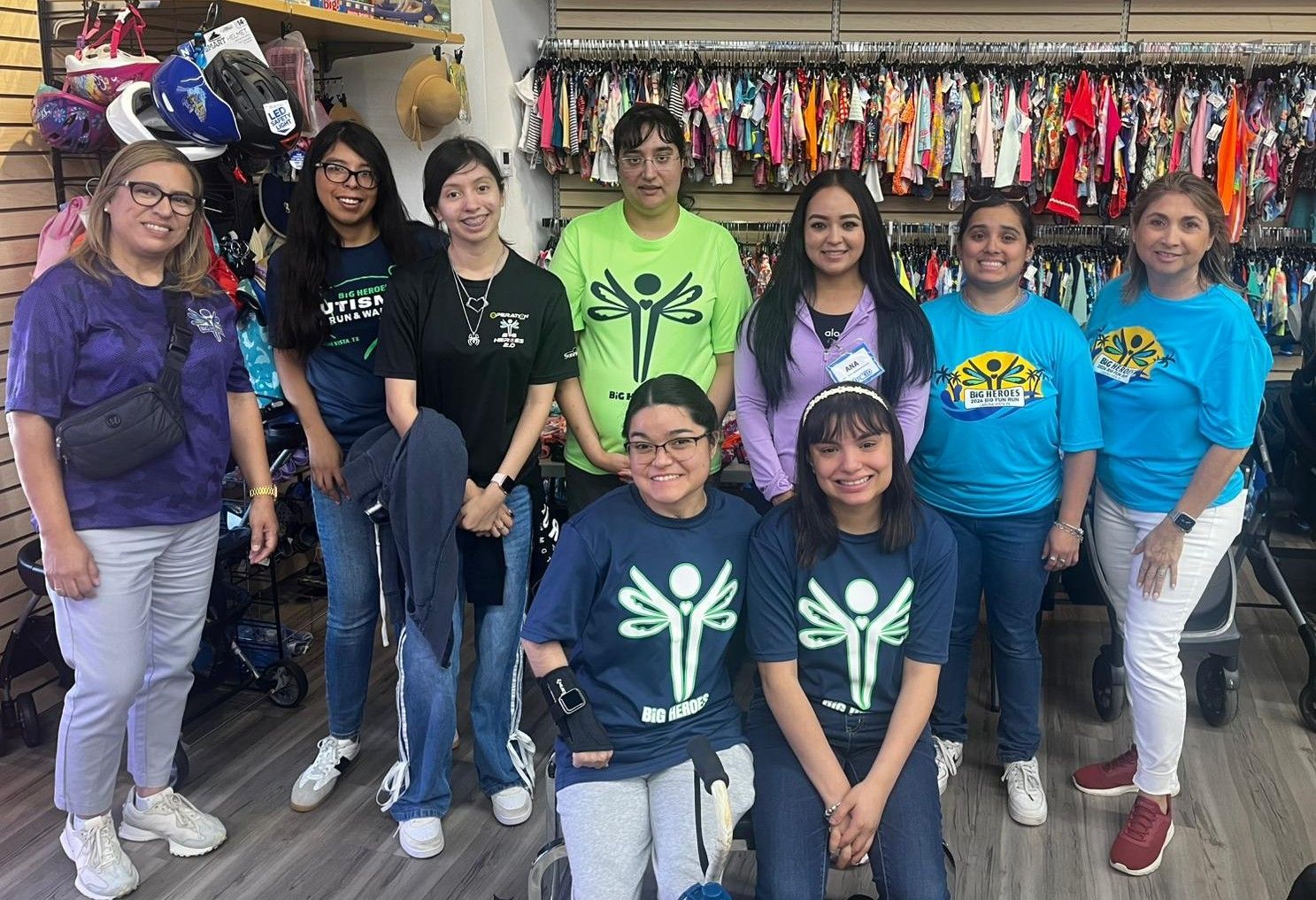 Group of people, mostly women, in a store, smiling. They are wearing various colored t-shirts and some are smiling.