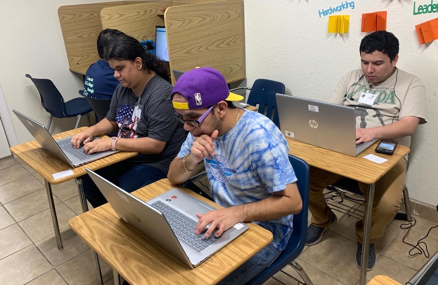 A group of people are sitting at desks using laptops.