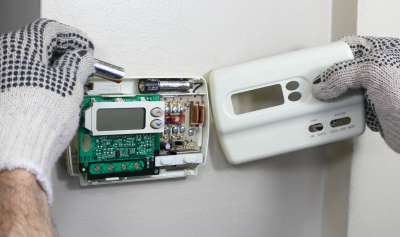 A HVAC technician installing at digital thermostat