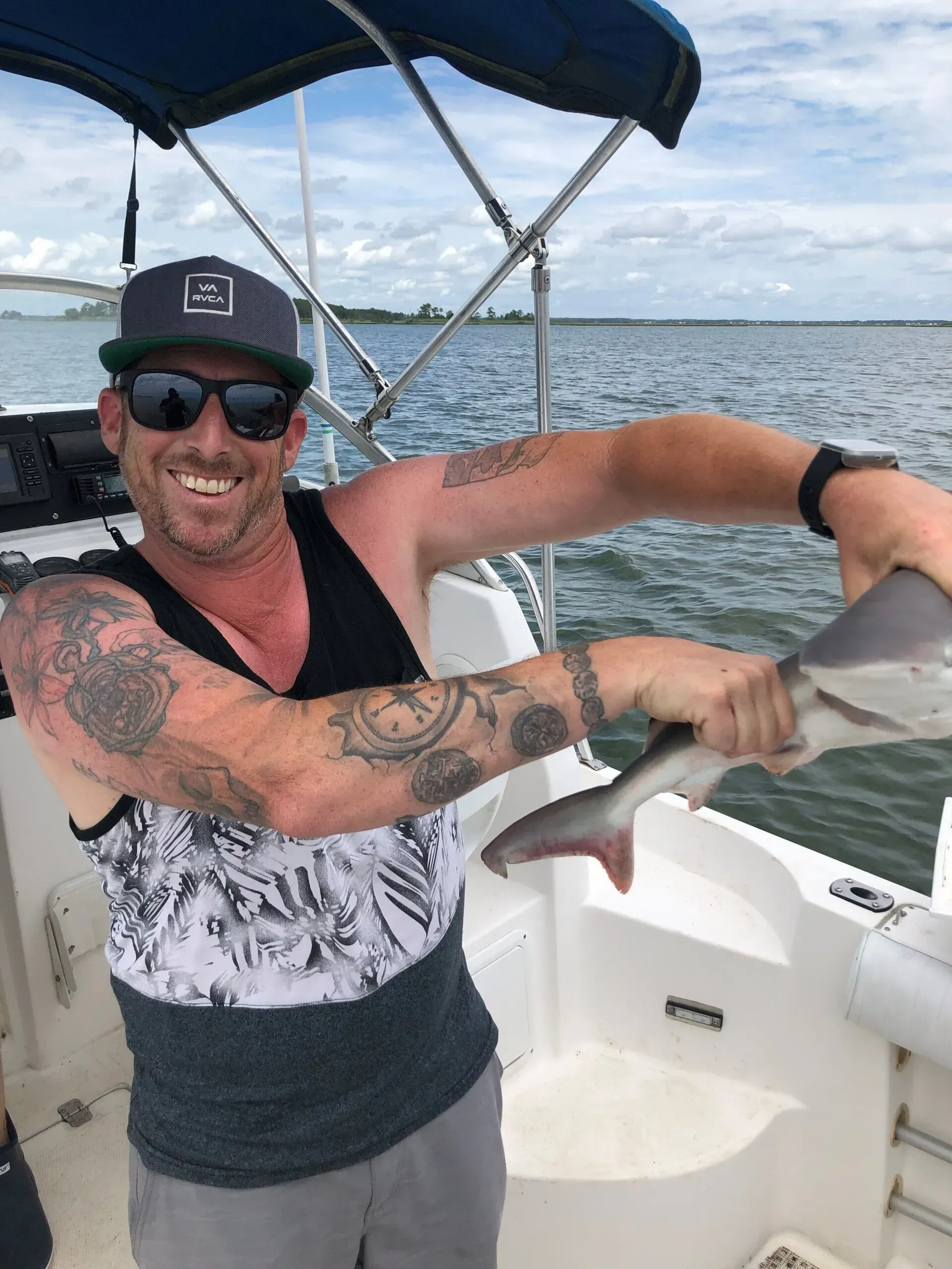 a man is holding a fish on a boat in the water .