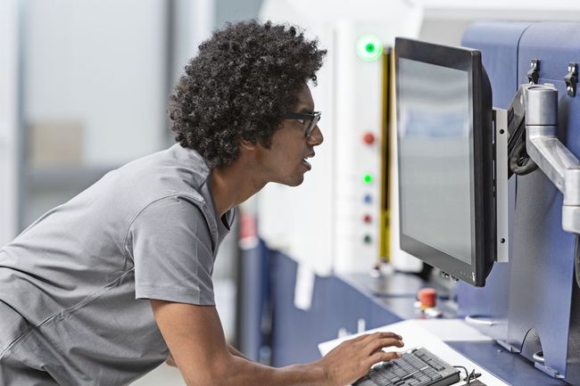 Postazione aziendale con stampante multifunzione, laptop con dashboard documentale e ambiente ufficio moderno e ordinato.