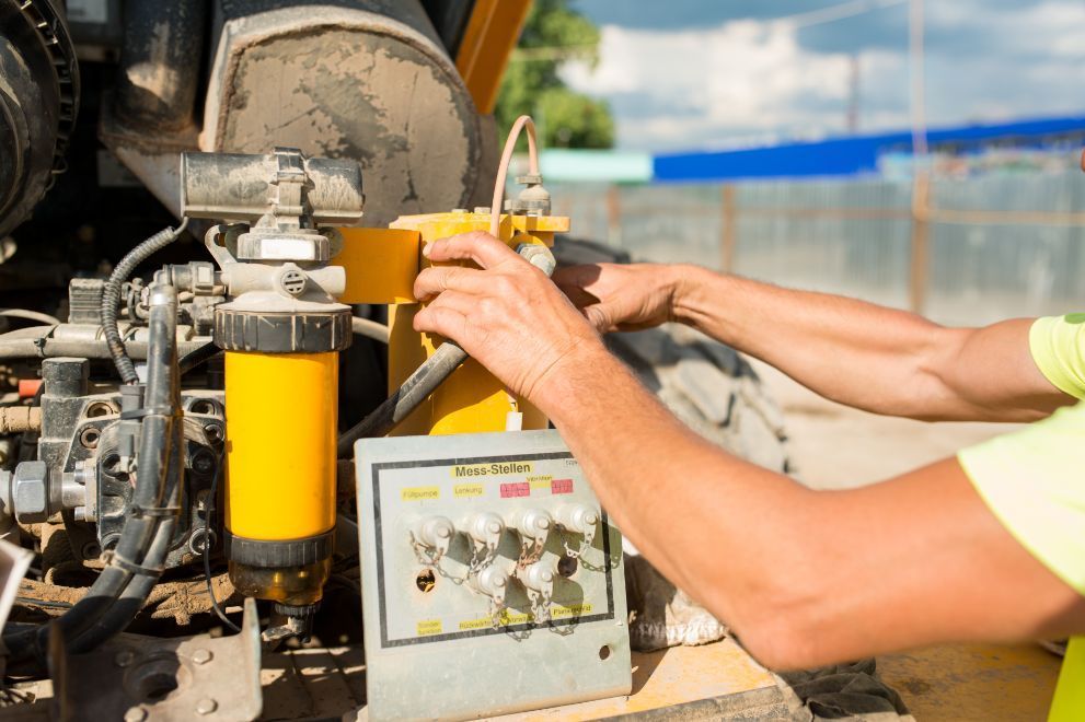 A man is working on a machine on a construction site.