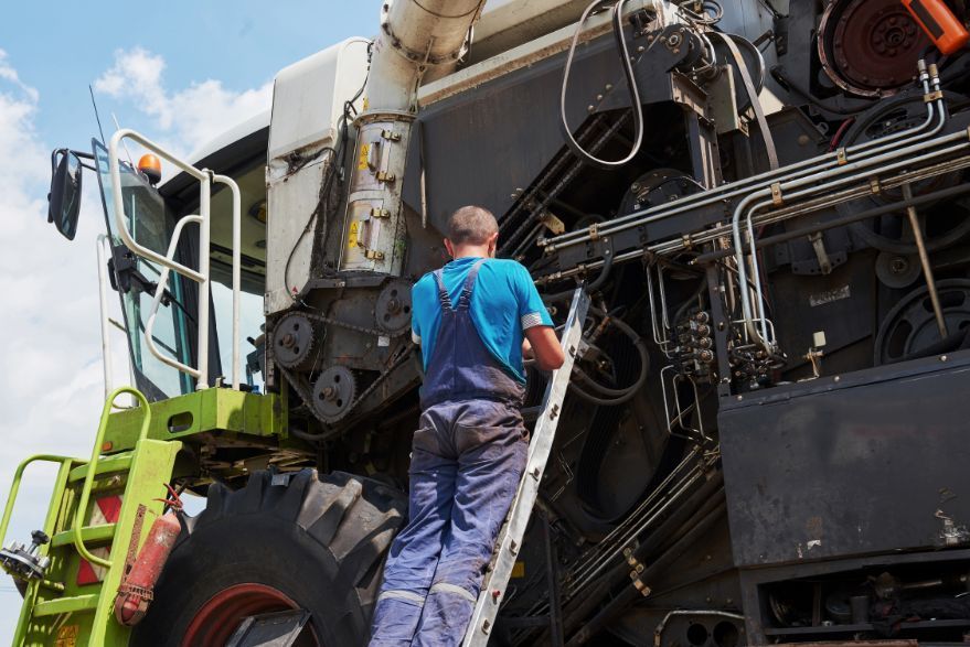 A man is standing on a ladder next to a tractor.