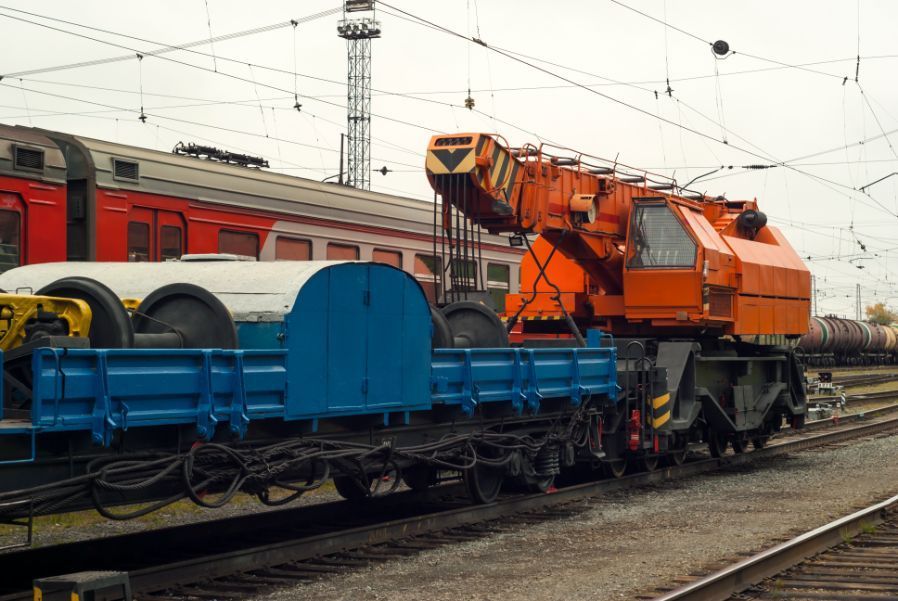 A train with a crane on the back of it is on the tracks.
