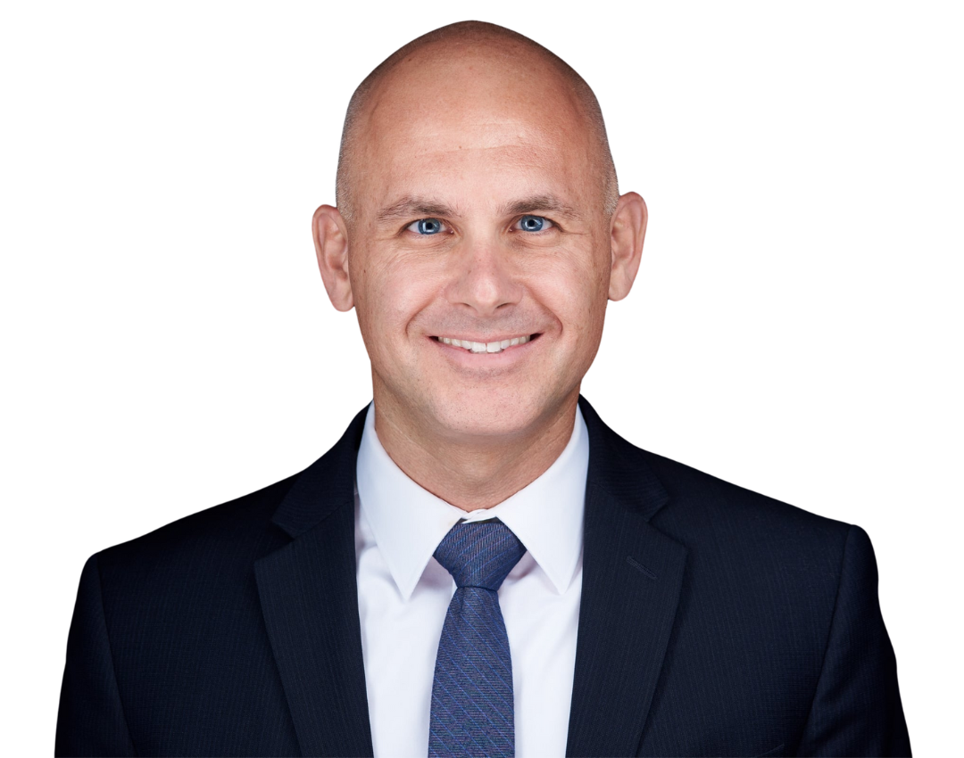 Bald man in a dark suit and tie, smiling at the camera against a white background.
