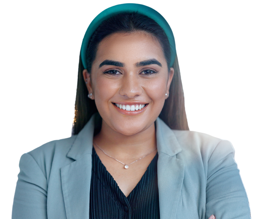 Woman in a blazer and teal headband smiles, arms crossed.