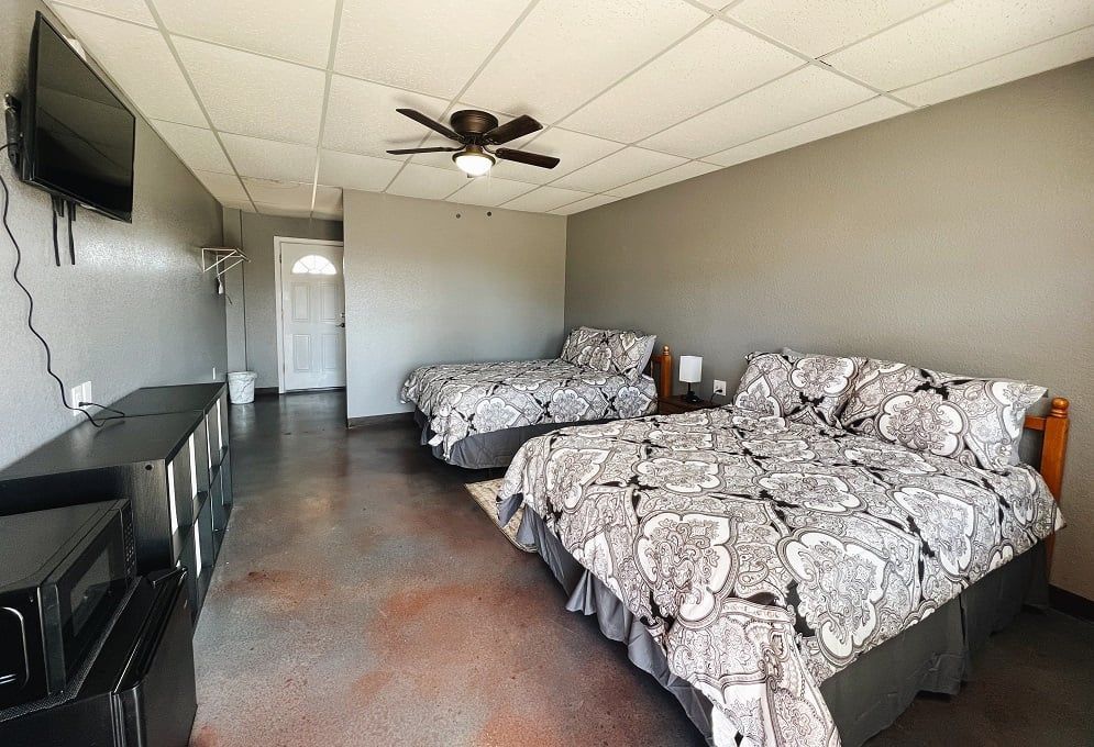 A motel room with two beds and a flat screen tv.