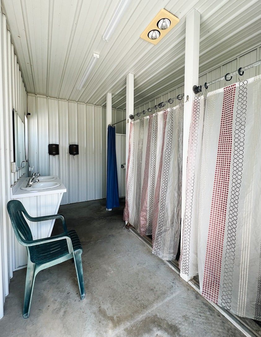 A shower room with a sink , chair and shower curtains