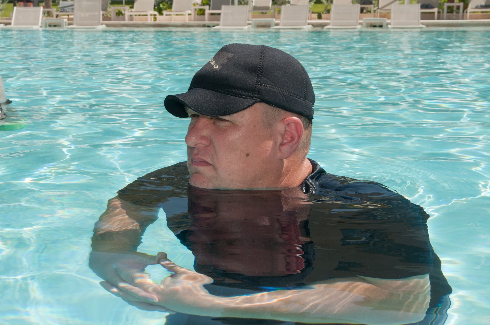 Chuck in a black hat is swimming in a pool