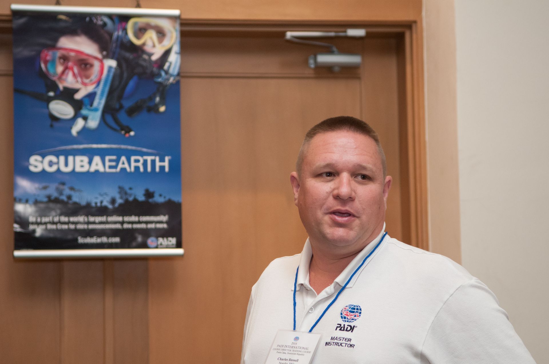 Chuck is standing in front of a sign that says scubaearth.