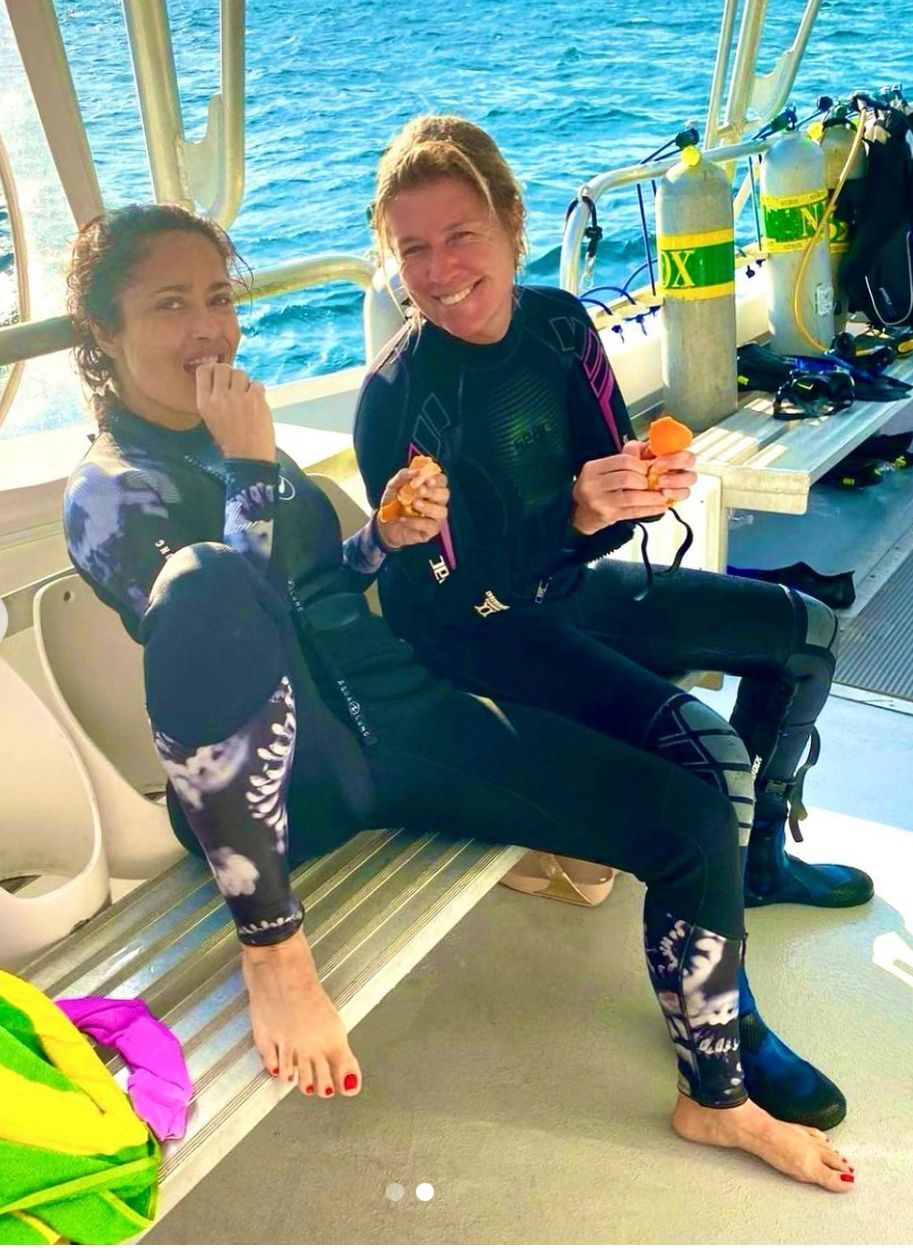 Two women are sitting on a bench on a boat eating food