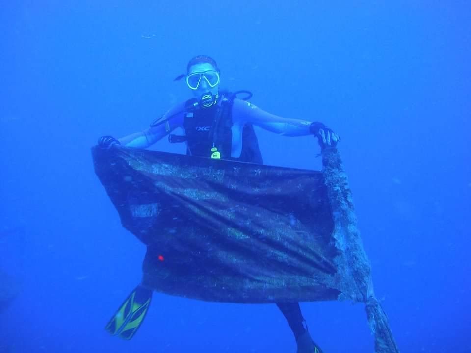 A scuba diver, Kathy, is holding a large piece of metal in the ocean.