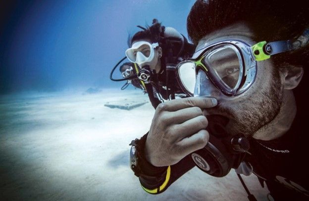 A man is taking a picture of another man while scuba diving.