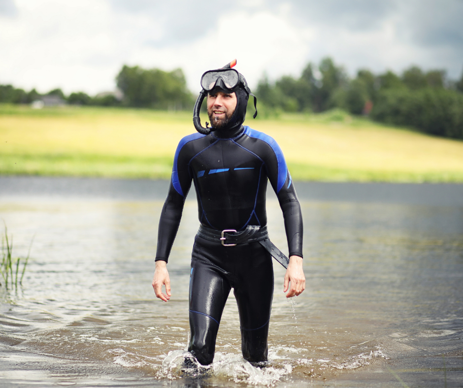 A man in a wetsuit and goggles is walking out of the water.