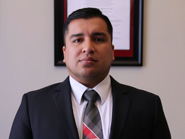 A man in a suit and tie is standing in front of a framed picture