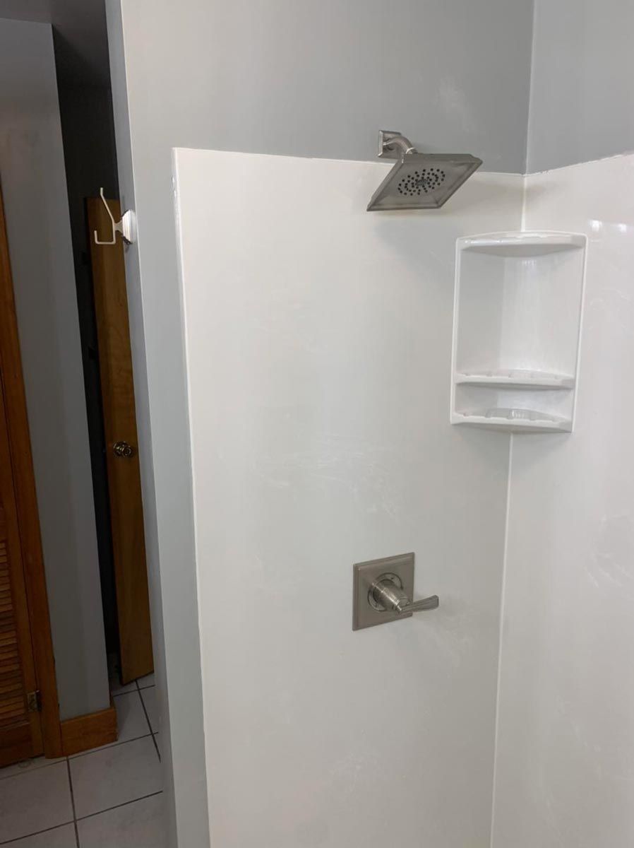 A shower stall with a shower head and a shelf in a bathroom in Danville, IL.