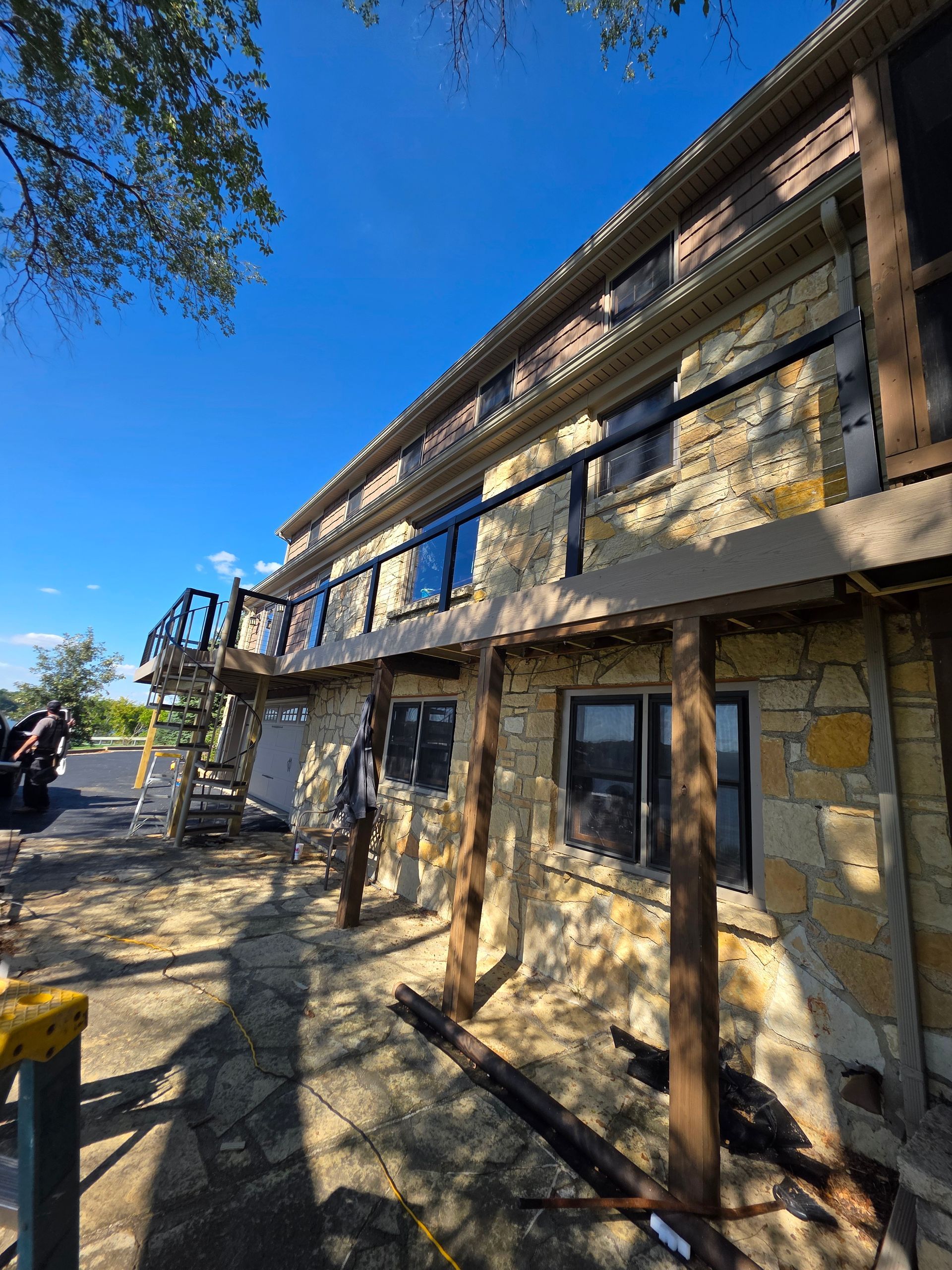A stone two-story building under a clear blue sky, featuring a balcony and support beams along the exterior wall - Danville, IL