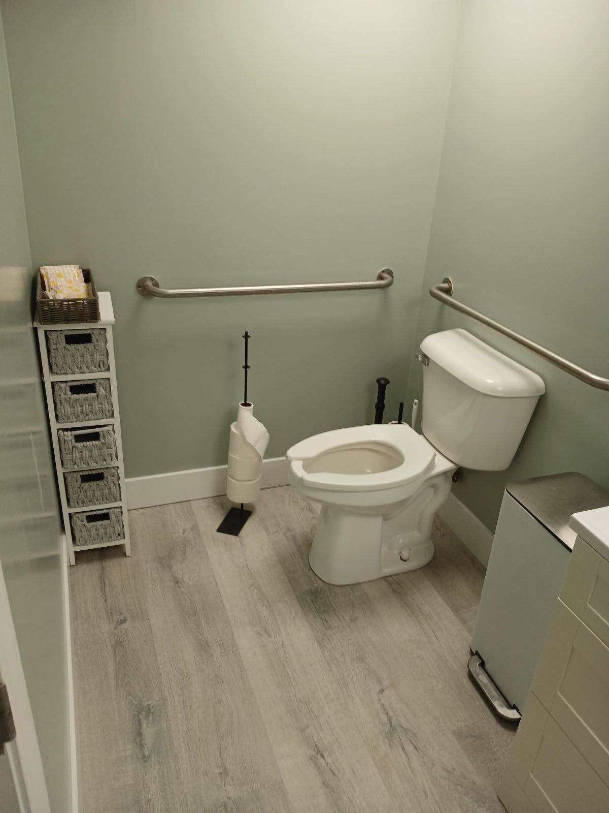 Bathroom with light gray walls, accessible toilet, grab bars, and storage shelves. | Urbana, IL