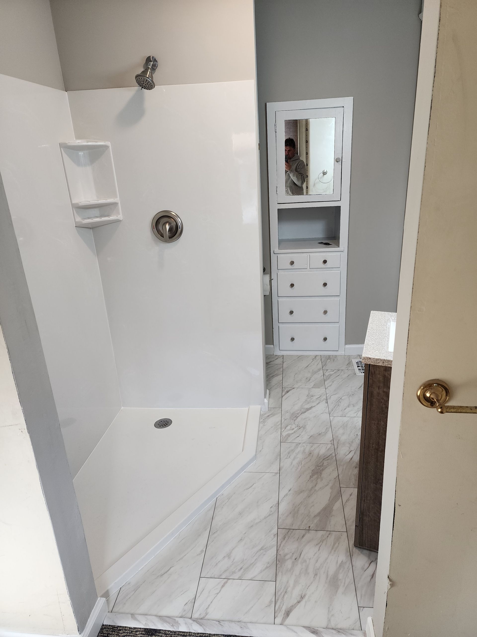 A shower stall with a shower head and a shelf in a bathroom in Danville, IL.