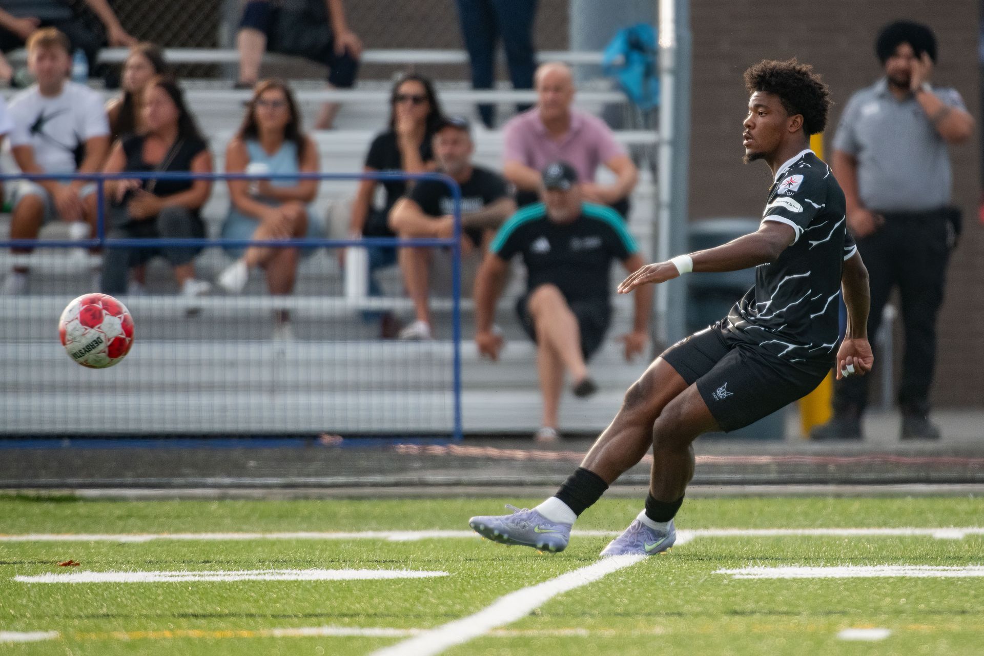 Scrosoppi FC player in action on the pitch in Milton with fans watching from the stands during a competitive soccer match