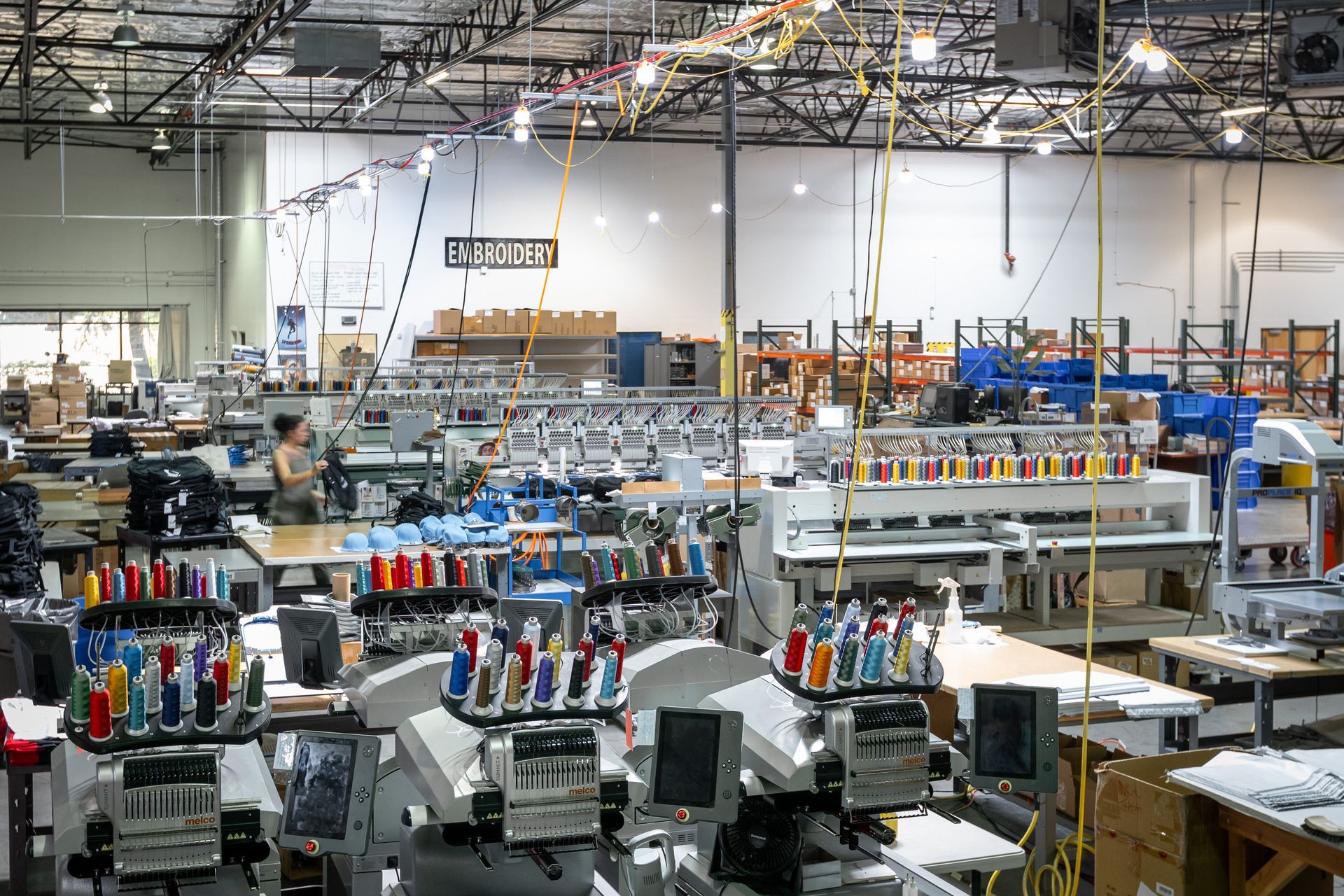 Image of 46 automated embroidery machines in a warehouse with a sign on the wall that reads embroidery