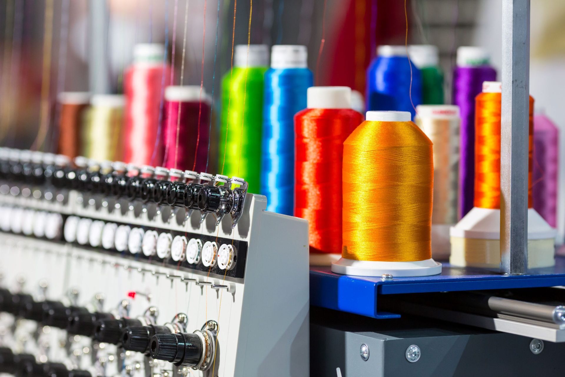 Close up of different color threads on top of an automatic embroidery machine
