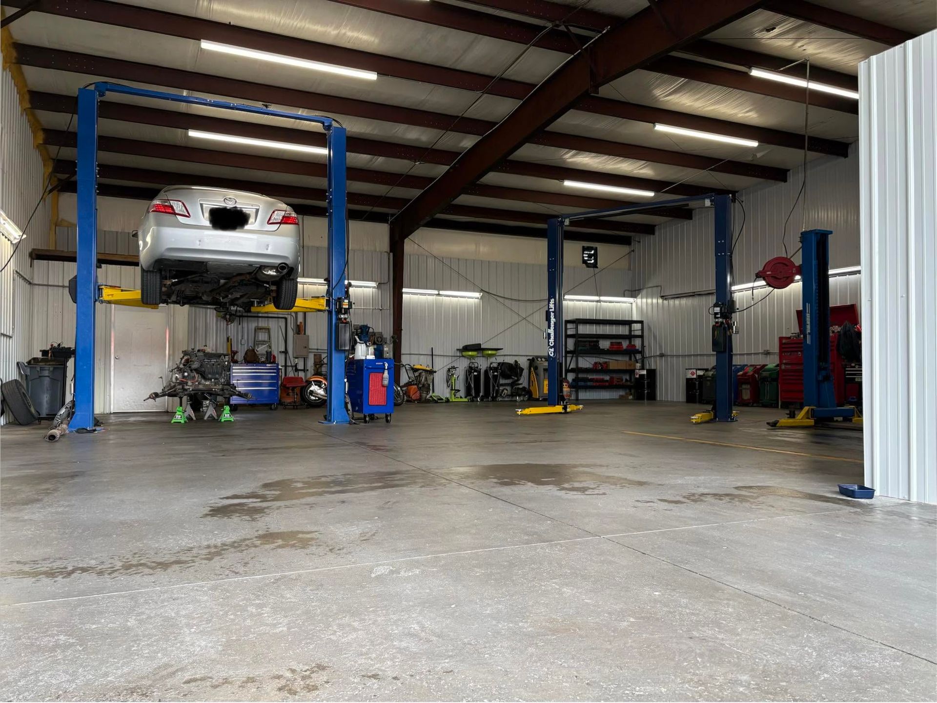 Auto repair shop with a car on a lift, tools, and service bays inside a large garage| Sonny's Automotive Repair and Sales