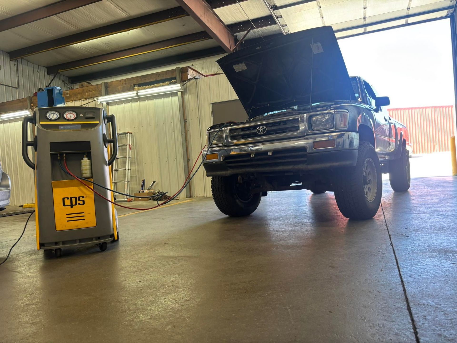 Classic pickup truck with hood open in an auto shop next to a yellow CPS charger.| Sonny's Automotive Repair and Sales