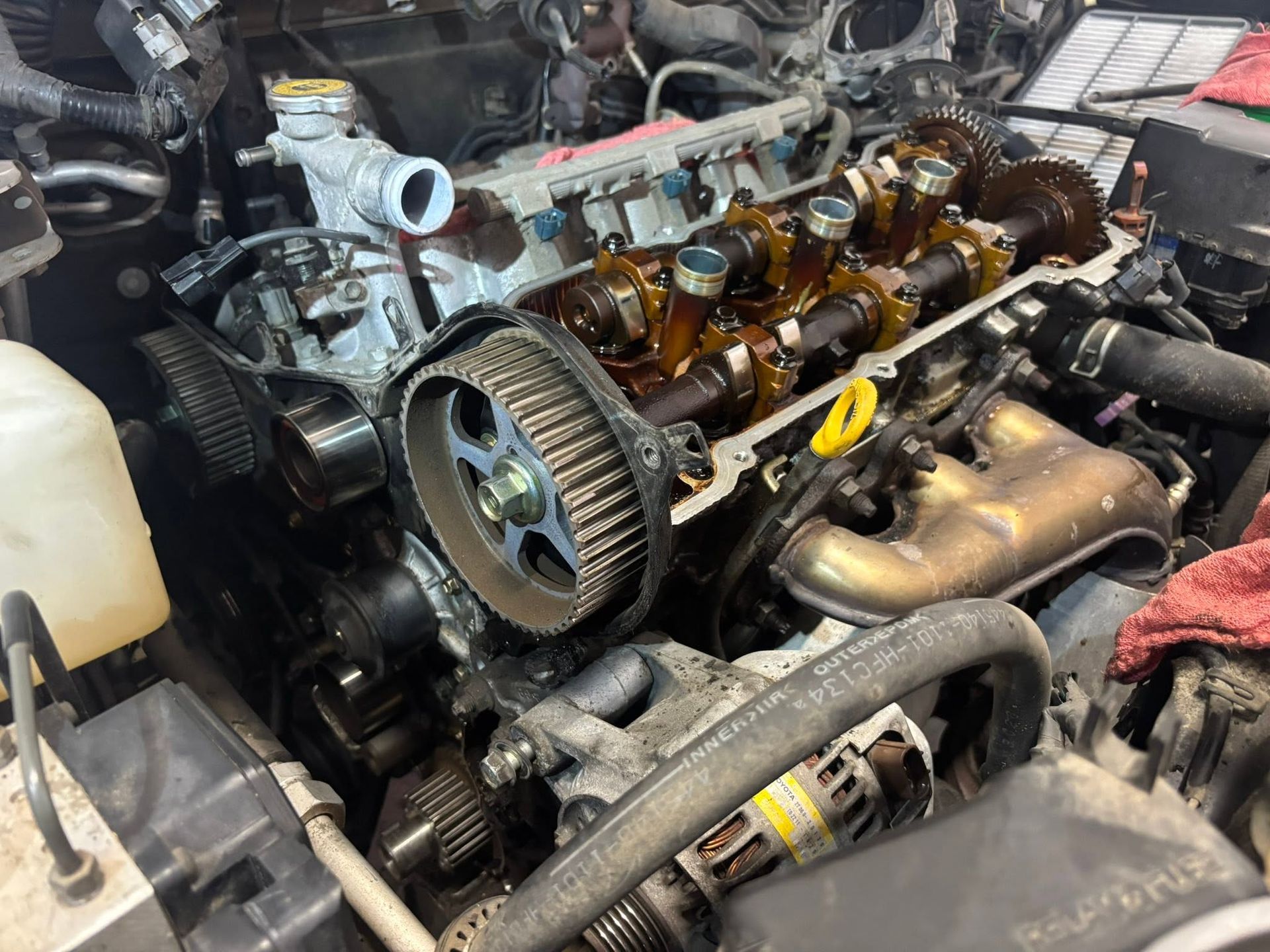 Car engine bay with exposed engine, camshaft, belts, and hoses during repair| Sonny's Automotive Repair and Sales